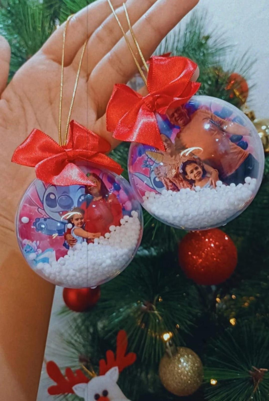 Duas bolas de Natal transparentes com fotos de família sobre fundo do Stitch, bolinhas de neve e laços vermelhos