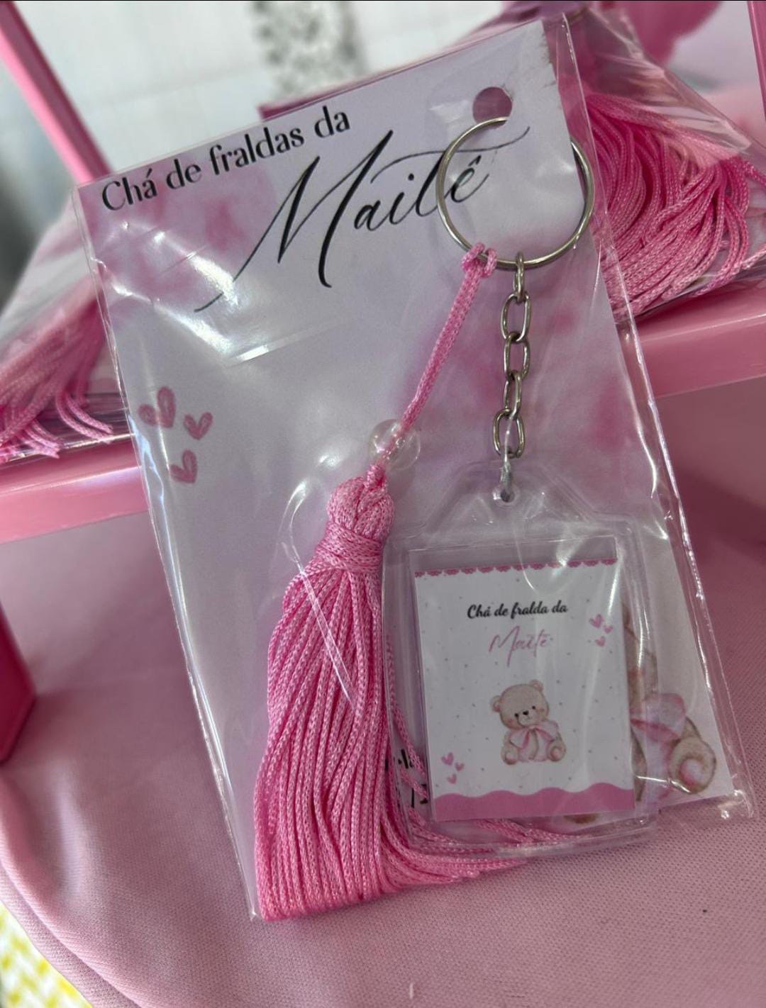 Chaveiro de acrílico com ursinho e tassel rosa, em embalagem com o texto Chá de fraldas da Maitê