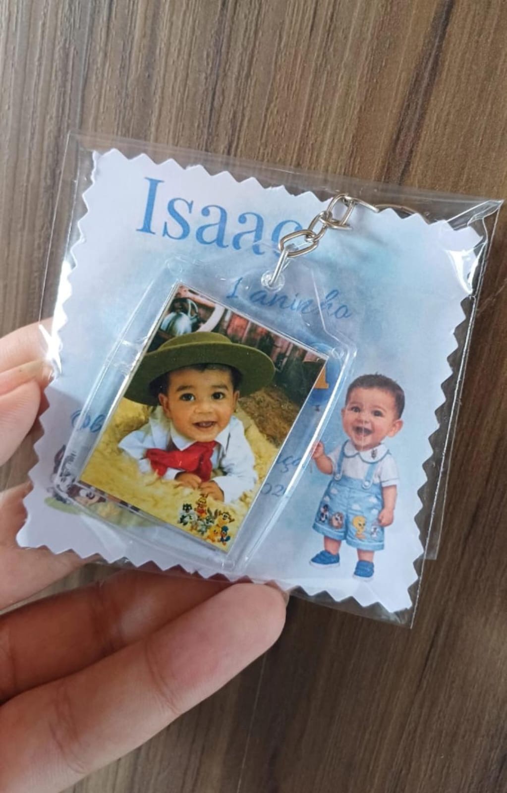 Chaveiro de acrílico com foto de bebê, em embalagem com cartão azul de aniversário de 1 aninho e o nome Isaac